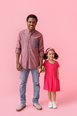 Portrait of little African-American girl and her father on pink background