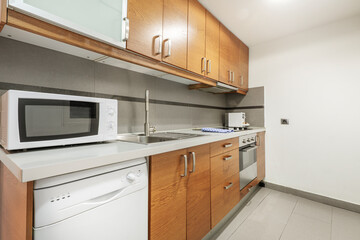 wooden kitchen with gray wooden countertop with white washing machine and matching microwave, gray ceramic tile floors