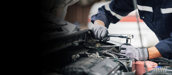 Mechanic works on the engine of the car in the garage. Repair service. Concept of car inspection service and car repair service.