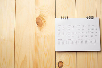 Calendar on wooden table with copy space, business meeting schedule, trip planning or project goals and reminder ideas.