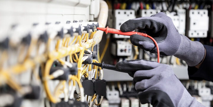 Electrician engineer tests electrical installations and wires on relay protection system. Adjustment of scheme of automation and control of electrical equipment.