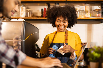 Young couple  manager in restaurant with digital tablet or notebook.Close up of joyful African American young woman worker in apron stands in cafe restaurant.Small business concept.
