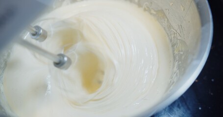 close up Electric mixer beating whips egg whites into fluffy cream meringue in the bowl for cake desserts and bakery	

