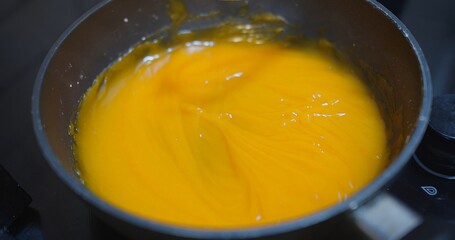 pastry chef cooking orange sweet icing glaze for decorating a cake in a restaurant kitchen or cake shop	
