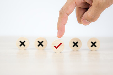 Hand choose check mark on wooden toy with cross symbol for true or false changing mindset or way of...