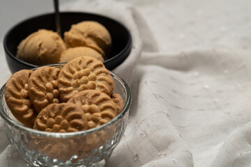 Tazón de galletas y tazón de helados alineados sobre una mesa con mantel blanco con textura 