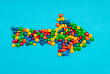 Arrow made with chocolate lunettes on a blue background.