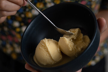 Textura de helado cremoso de vainilla sobre un plato negro de cerámica 