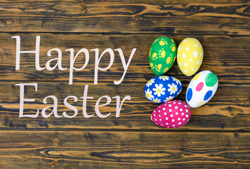 easter eggs in a nest on a wooden background with the inscription happy easter top view 