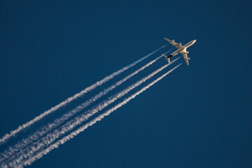 four engine jet aircraft flying in the sky with contrail