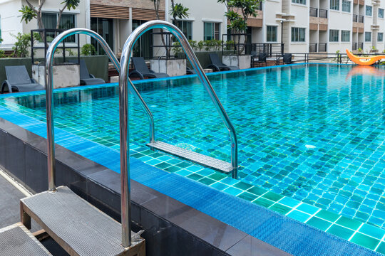 Ladder stainless handrails for descent into swimming pool. Swimming pool with handrail . Ladder of a swimming pool. Horizontal shot. stairs swimming pool. Stainless steel ladder © kanpisut