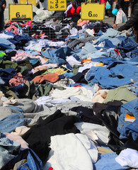 stalls of new and used clothing with clothes scattered in the open air market