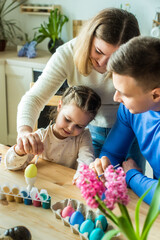 the family paints colorful Easter eggs. mom, dad and daughter celebrate spring holiday together