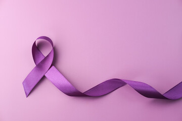 Purple ribbon as symbol of World Cancer Day over purple color background, copy space.
