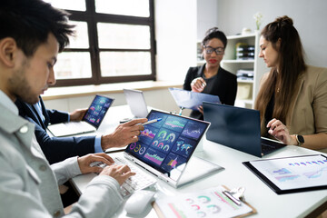 Side View Of Businesspeople Examining Graph On Computer