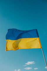 The flag of Ukraine is a large national symbol flying in the blue sky. Large yellow and blue state flag of Ukraine.