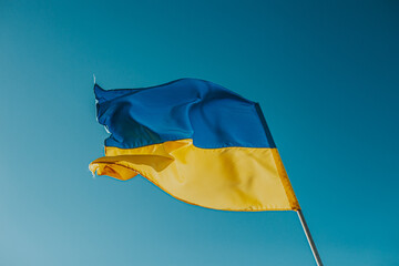 The flag of Ukraine is a large national symbol flying in the blue sky. Large yellow and blue state flag of Ukraine.