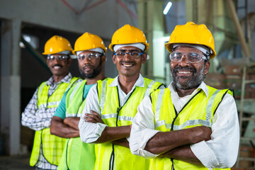 Confidently standing industrial workers with arms crossed by looking at camera - concept of...