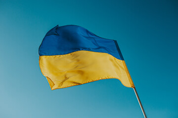 The flag of Ukraine is a large national symbol flying in the blue sky. Large yellow and blue state flag of Ukraine.