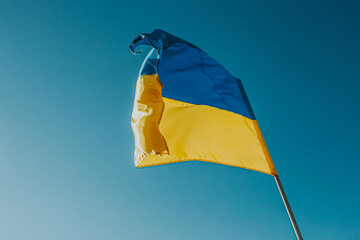 The flag of Ukraine is a large national symbol flying in the blue sky. Large yellow and blue state flag of Ukraine.