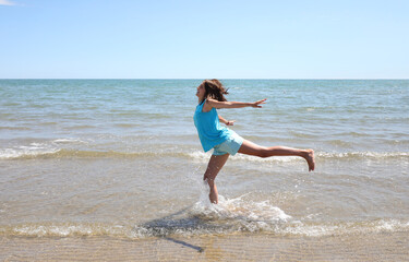 young athletic girl performing gymnastic exercises on the seashore