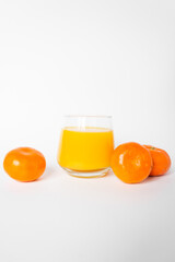 Glass of fresh orange juice with three citrus mandarin fruits near. Isolated on the white background.