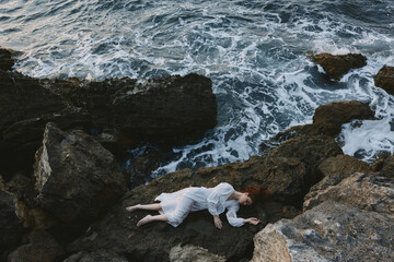 beautiful woman lying on rocky coast with cracks on rocky surface vacation concept