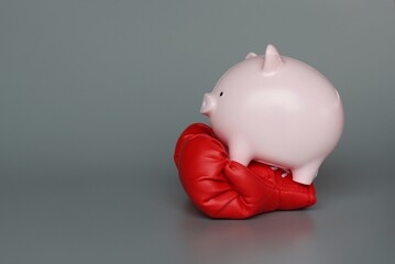 Piggy bank and boxing gloves on grey background with copy space. Protect savings, financial concept.
