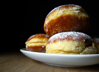 Polish pączki (deep-fried doughnuts). Celebrating Fat Thursday (Tłusty czwartek) feast, traditional day in Poland. Pączek food, powdered sugar topped and filled with rose hip jam.