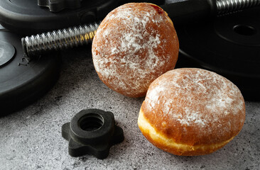 Dumbbells barbell weight plates and Polish pączki deep-fried doughnuts. Fat Thursday (Tłusty...