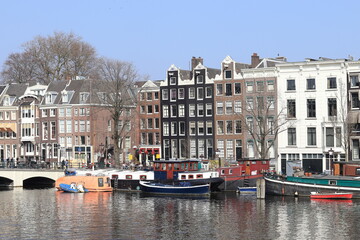 Fototapeta na wymiar Amsterdam Amstel River View with Houseboats, Bridge and Historic Architecture, Netherlands