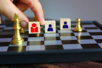 hand holding wood block with red people icon plan put on chess board , idea working concept