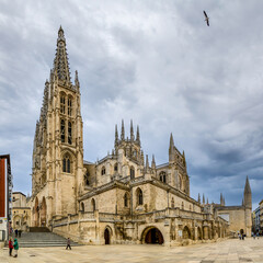 Fototapeta na wymiar Burgos Cathedral with people and tourists walking past in the square next to the Cathedral of Saint Mary