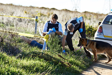 Sniffing out a suspect. Shot of two investigators taking notes while examining a body at a crime...