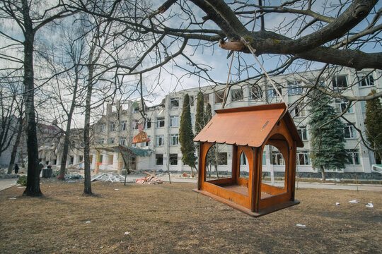 Zhytomyr, Ukraine - March 16, 2022: consequences of the bomb dropped on the school. Russian military attacks from the air. Bird feeder at foreground
