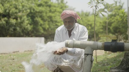 Happy Indian farmer after seeing water on borewell pipe at farmland - cocnept of happiness, poverty and water for agricultural works - Powered by Adobe