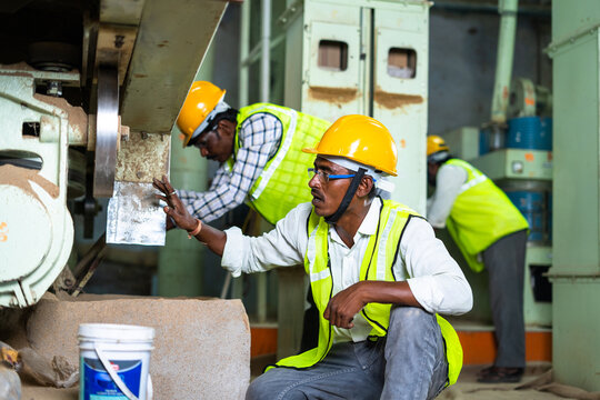 Industrial Workers Busy Working On Machinery With Safety Helmet At Factory - Concept Of Blue Collar Jobs, Teamwork And Occupation