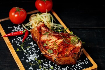 Grilled meat on a stone board. Appetizing Pork steak with herbs and spices. Close-up