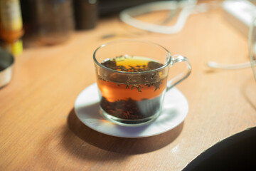 Tea in clear cup. Drink is hot. Tea leaves in boiling water.