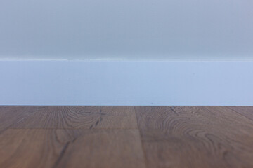 White baseboard, white wall and wood laminate.