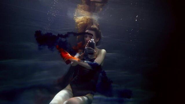 charming woman is swimming underwater and playing with blue and red colors, art and fantasy shot