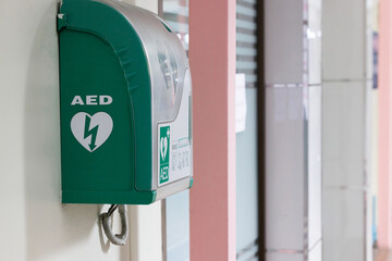 Automated external defibrillator in green box hang on wall in hospital. AED medical first aid device. - obrazy, fototapety, plakaty