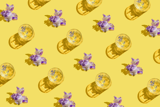 Creative pattern made of beautiful iris flowers on yellow background. Summer refreshment concept. Sunlit flat lay. Minimal style. Top view.