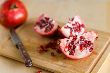 Pomegranate and knife on wooden background, close up shot.