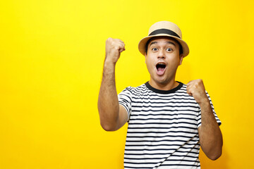 Portrait of cheerful asian man in basic clothing Casual wear hat smiling and show giving thumbs up at camera with showing success. isolated over yellow background.