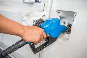 Hand holding blue fuel nozzle Car Gas Tank. Petroleum, energy and transportation concept. 