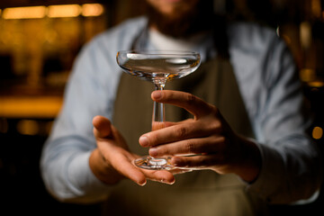 Close-up front view on elegant transparent wine glass in male hands