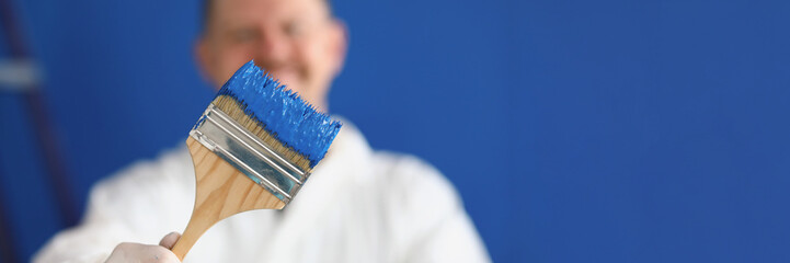 Man holding paintbrush with blue paint close-up