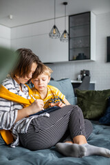 brother and sister playing on the tablet sitting on the couch