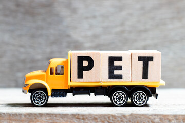 Truck hold letter block in word pet on wood background